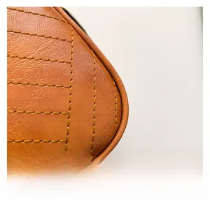Macro detail of orange leather textured handbag with decorative diamond stitching