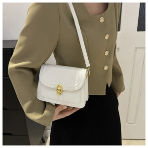 Detail of white leather crossbody bag showing golden horseshoe buckle and fine stitching