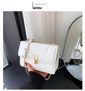 Détail du matelassage géométrique blanc et du fermoir doré en forme de U sur le sac à main