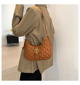 Sac sous le bras matelassé marron caramel avec boucle dorée porté par un mannequin