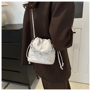 Close-up of beige quilted bucket bag with silver chain detail and drawstring closure