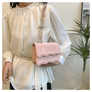 Detail of pink wave-edge crossbody bag showing the chain strap and metal adjustment ball