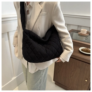 Detail of black quilted corduroy hobo bag showing texture and stitching on wide shoulder strap