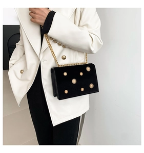 Détail du sac bandoulière en velours noir avec chaîne dorée et rivet tournesol