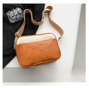 Detail of color-block crossbody bag featuring V-shaped quilting and wide fabric strap
