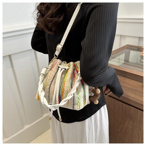 Vertical striped bucket bag with drawstring closure and cute plush monster pendant detail
