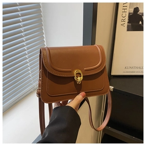 Detail of vintage brown leather crossbody bag featuring gold interlaced rings buckle