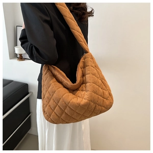 Detailed view of yellow corduroy quilted tote bag shown on a model's shoulder