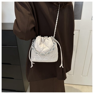 Detail of cream white bucket bag featuring quilted rhombic pattern and silver chain