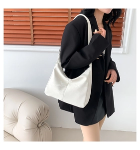 Chic cream leather hobo bag with stitched detail shown on a stylish model's shoulder