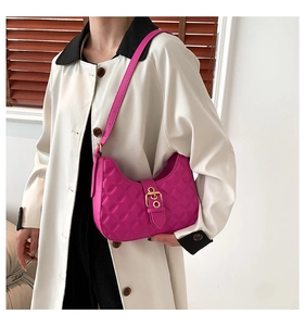 Détail du sac à main matelassé rose fuchsia avec boucle dorée porté par un modèle