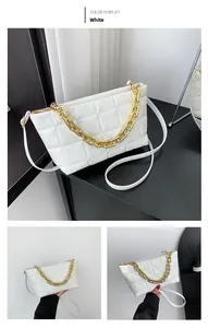 Detailed view of the white quilted crossbody bag with bold golden chain and leather strap