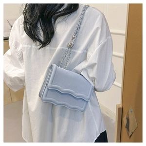 Detail of light blue wave-pattern crossbody bag with silver chain and Merry Love text