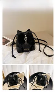 Detail view of black drawstring bucket bag with smooth leather finish and metal buckle