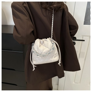 Detail of a beige quilted bucket bag with silver chain handle and drawstring closure