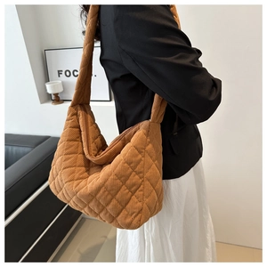 Detailed side view of brown corduroy quilted tote bag shown on model for size and scale