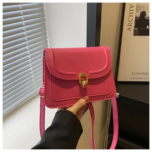 Close-up of bright rose red leather crossbody bag with golden oval double-ring buckle