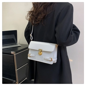 Detail of white rectangular crossbody bag with golden round buckle on a black suit