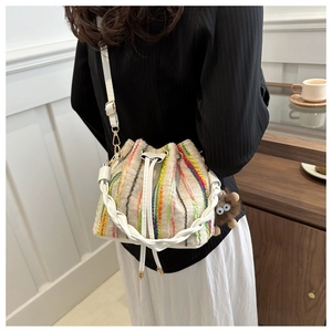 Vertical striped bucket bag with colorful woven patterns and a cute monster charm
