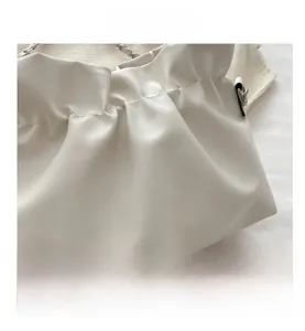 Close-up of white ruched faux leather bag showing stitching details and silver chain strap