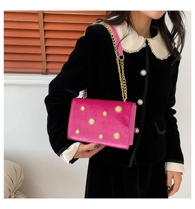 Détail du sac à bandoulière en velours fuchsia avec clous soleil dorés et chaîne en métal