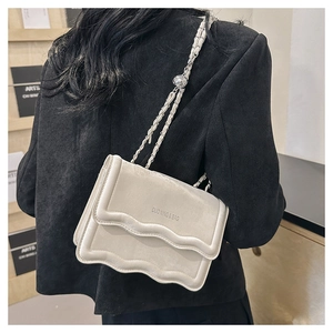 Detail of cream white wave edge crossbody bag with silver chain and metal adjuster