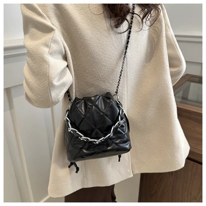 Detail of black quilted bucket bag featuring a drawstring closure and dual chain straps