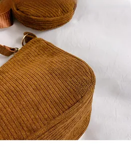 Detailed macro view of brown corduroy fabric texture on a crossbody bag with round pouch