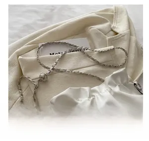 Detail of white drawstring bucket bag with silver chain strap and adjustable metal bead