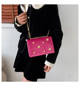 Détail du sac bandoulière en velours fuchsia avec boucles tournesol dorées et chaîne