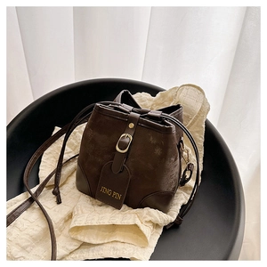 Detailed macro shot of vintage brown bucket bag with golden buckle and textured finish