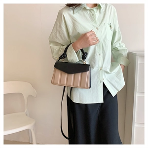 Detail of color-block handbag with pleated texture and black knotted handle for women