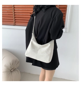 Close-up of minimalist white shoulder bag with marble texture worn by a model in soft light