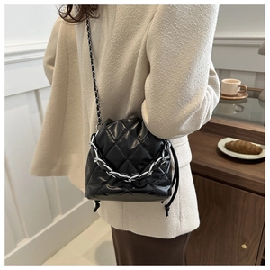 Quilted black bucket bag with silver chain handle displayed in an elegant lifestyle setting