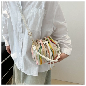 Detail of colorful striped tweed bucket bag with drawstring closure and braided handle