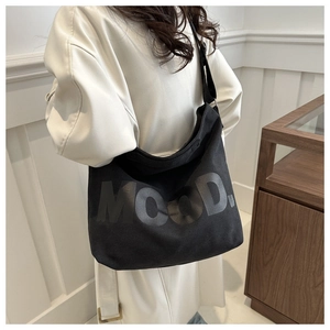 Modell mit großer schwarzer Canvas-Umhängetasche mit MOOD-Schriftzug im minimalistischen Stil