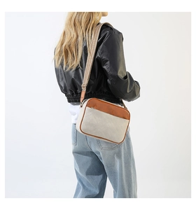 Detailed view of the contrast color leather crossbody bag with wide woven shoulder strap