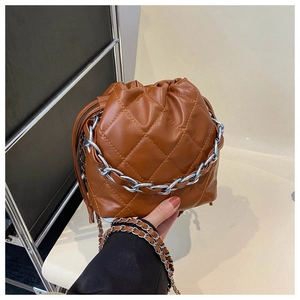 Detail of brown quilted bucket bag with drawstring closure and silver chain strap