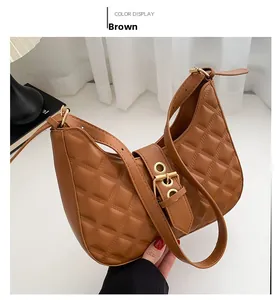 Détail d'un sac à bandoulière marron matelassé en demi-lune avec une boucle en métal