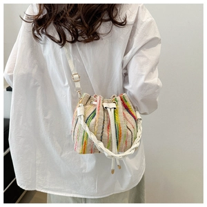 Detail of colorful woven bucket bag with striped patterns and leather drawstring closure
