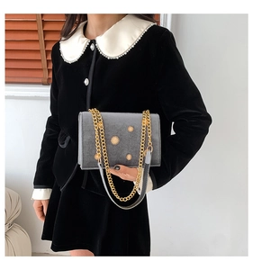 Sac carré en velours gris avec rivets tournesol dorés et bandoulière chaîne sur modèle