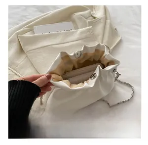 Detailed top view of white ruched bucket bag with silver chain and magnetic closure