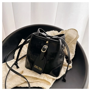 Close-up of black bucket bag featuring golden buckle and textured matte synthetic leather