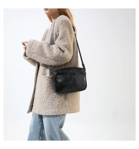 Detail of retro black crossbody bag with herringbone texture worn by a model