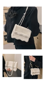 Detailed view of the wavy pleated edge and silver chain strap on the beige PU crossbody bag