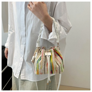 Detail of colorful striped drawstring bucket bag with white woven handle and leather strap
