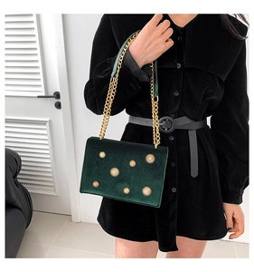 Détail du sac en velours vert foncé avec rivets dorés et bandoulière chaîne