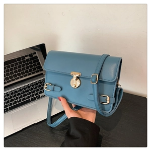 Detailed view of navy blue leather crossbody bag with golden round clasp and adjustable strap