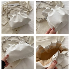 Detail view of white ruched cloud bucket bag with silver chain and magnetic closure