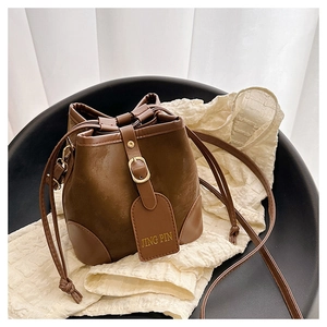 Detail of vintage brown drawstring bucket bag with textured leather and gold tag